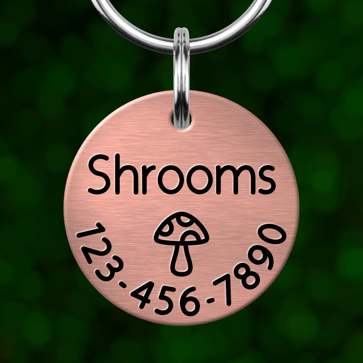 A round metal tag with the word "Shrooms" printed on it, along with a mushroom icon and a phone number.