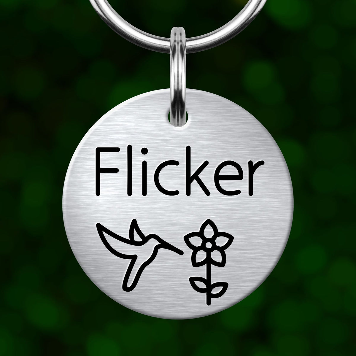 A round metal keychain tag with the name "Flicker" and a bird and flower symbol printed on it.