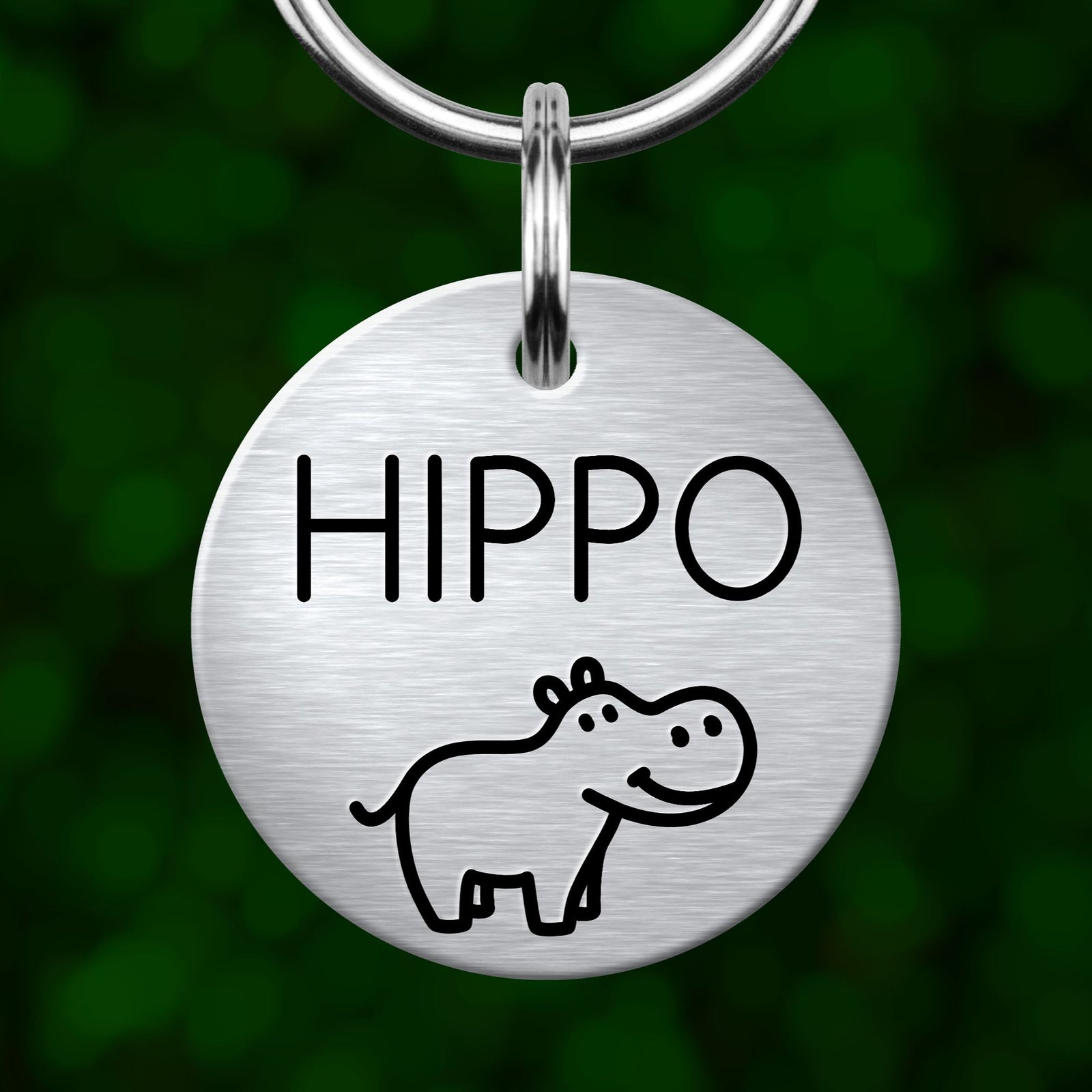 A round metal keychain tag with the word "Hippo" written on it, featuring a simple cartoon illustration of a hippopotamus.