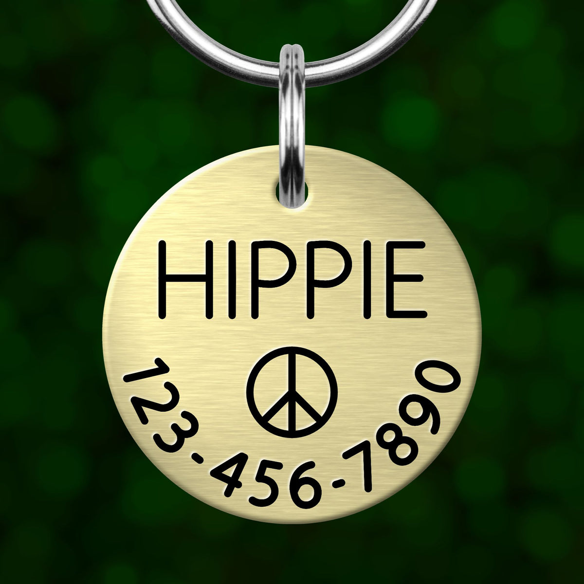 A round metal pet tag with the word "HIPPIE" printed on it, along with a peace symbol and a phone number.
