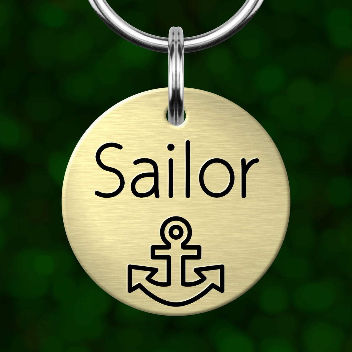 A round metal keychain tag with the word "Sailor" printed on it, along with an anchor symbol.