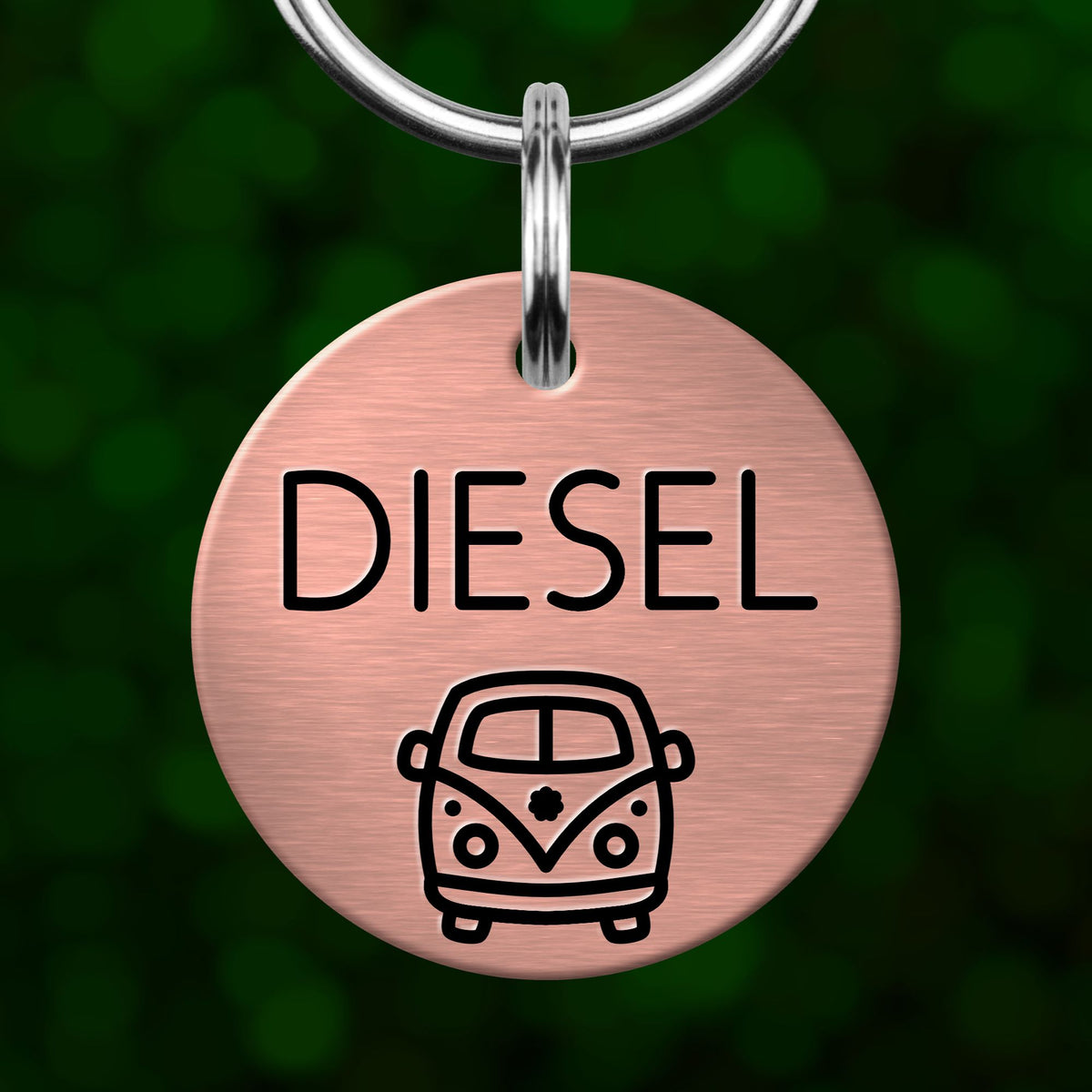 A round metal dog tag with the word "DIESEL" printed on it, featuring a small illustration of a van below the text.