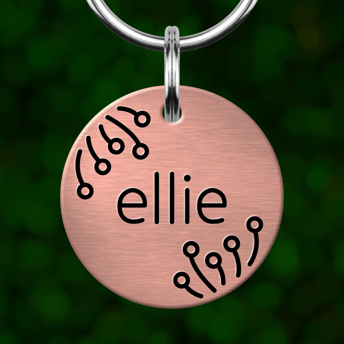A round, metallic dog tag with the name "Ellie" engraved on it.