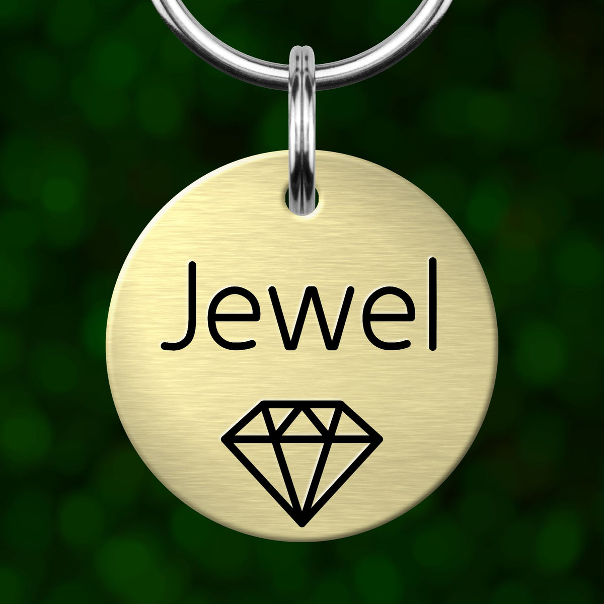 A round metal pet tag with the word "Jewel" printed on it, along with a graphic of a diamond.