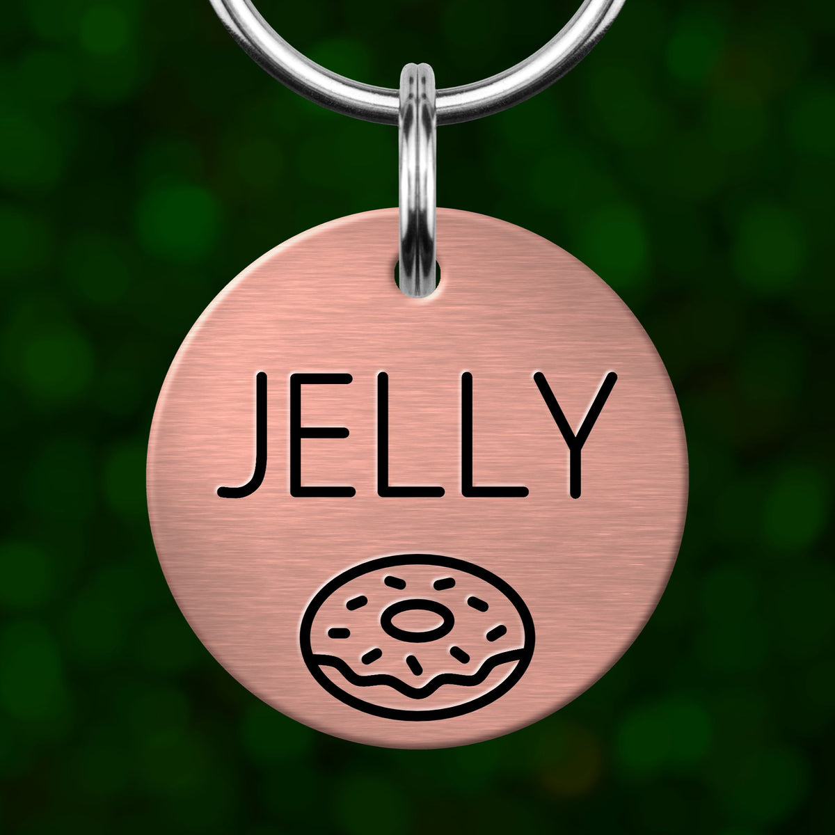 A round metal dog tag with the word "JELLY" printed on it, along with a simple illustration of a donut.