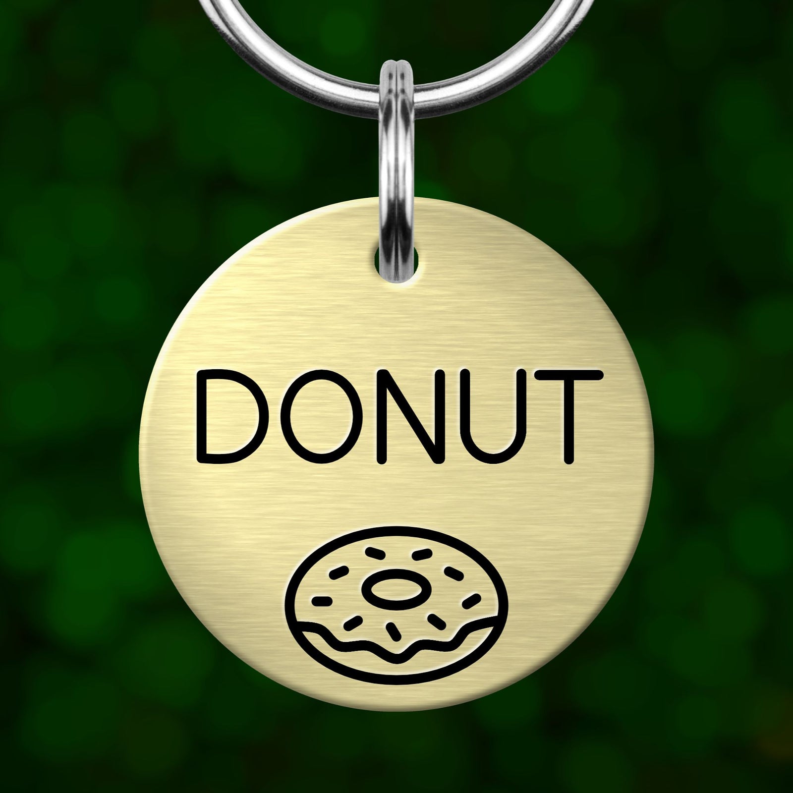 A round metal dog tag with the word "DONUT" printed on it, along with a simple illustration of a donut.