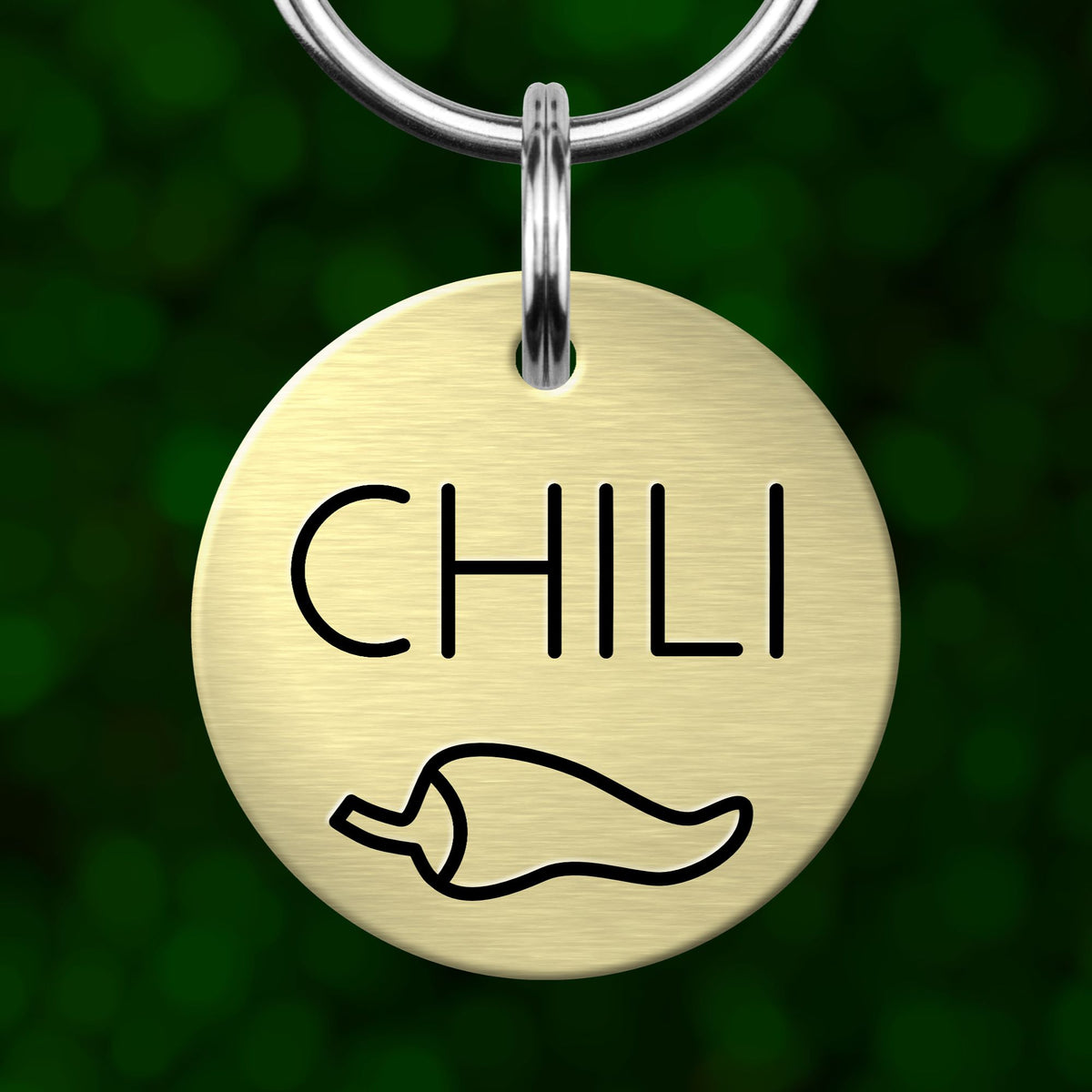 A round metal dog tag with the word "CHILI" printed on it, along with a simple black outline of a chili pepper.