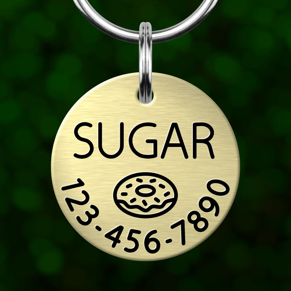 A round metal pet tag with the word "SUGAR" printed on it, along with a graphic of a donut.