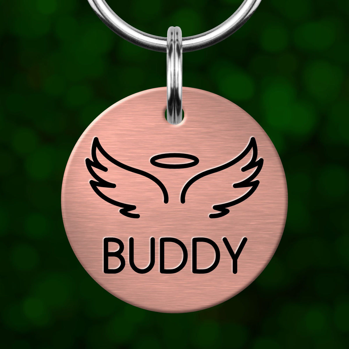 A pink circular pet tag with a graphic of wings and the word "Buddy" printed on it.