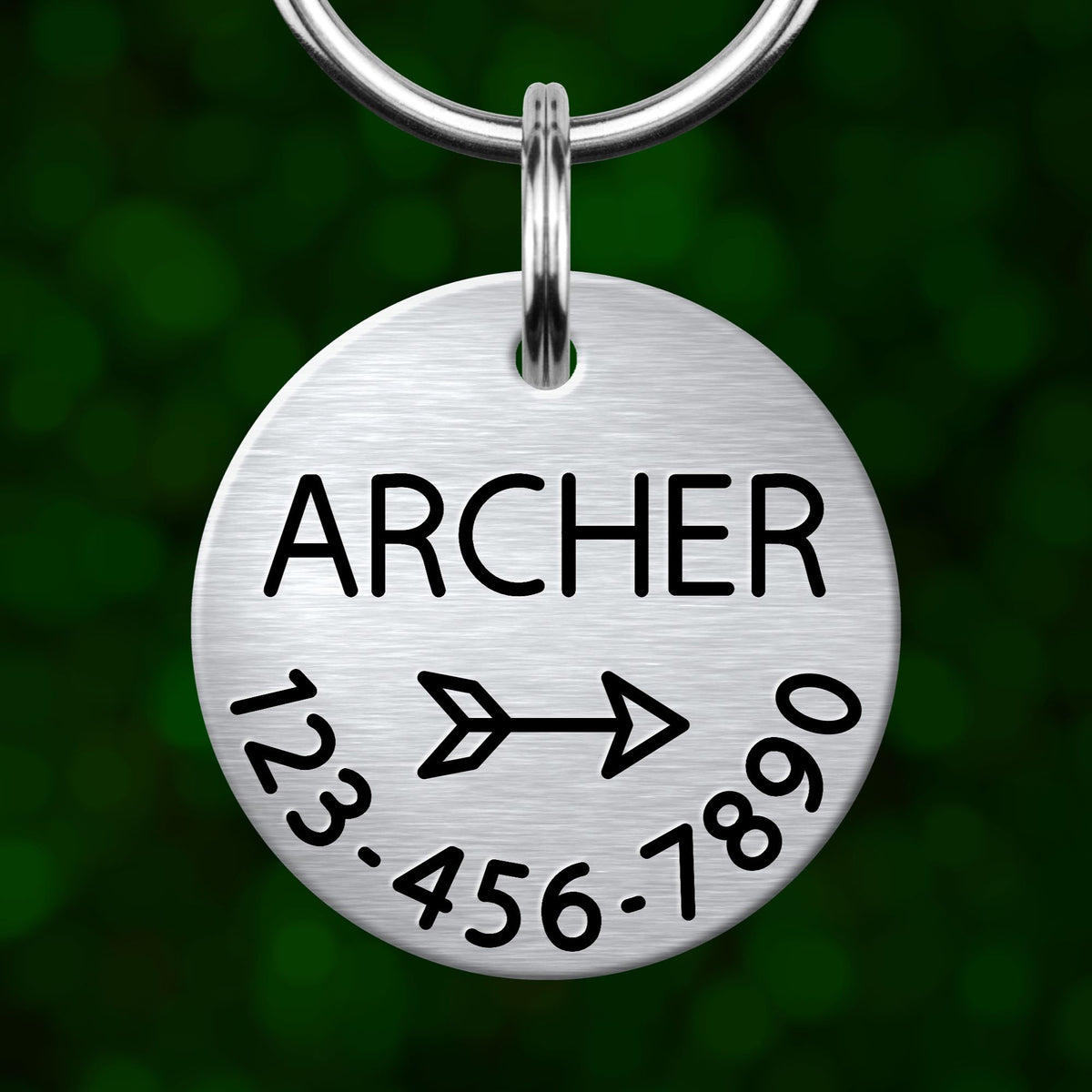 A silver metal name tag with the name "ARCHER" and a phone number on it, hanging from a keychain.