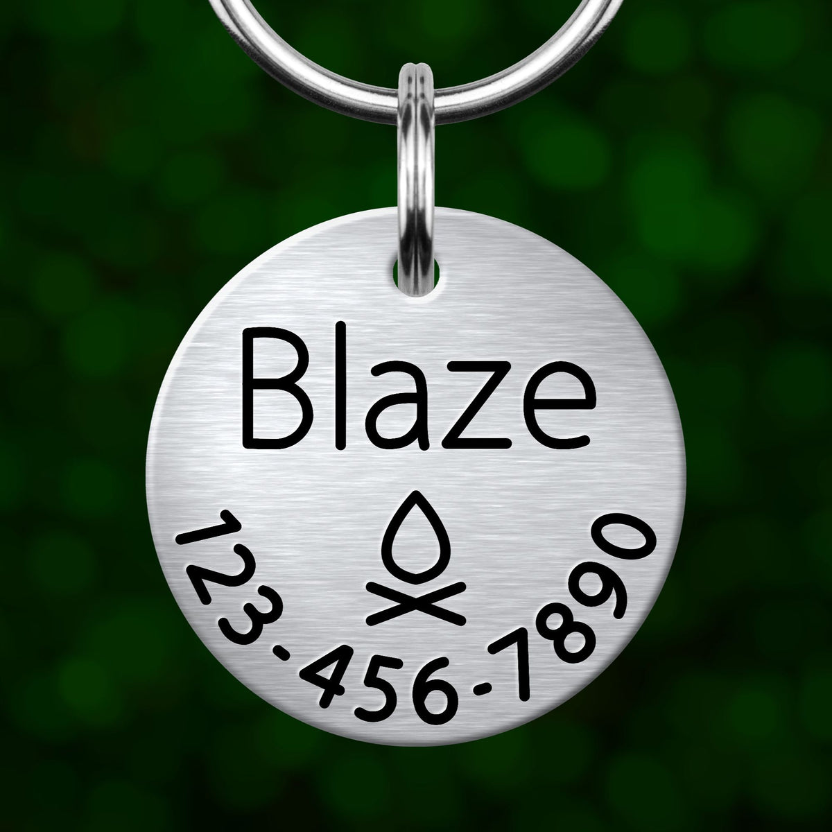 A silver-colored metal name tag with the name "Blaze" printed on it, along with a phone number and a symbol.