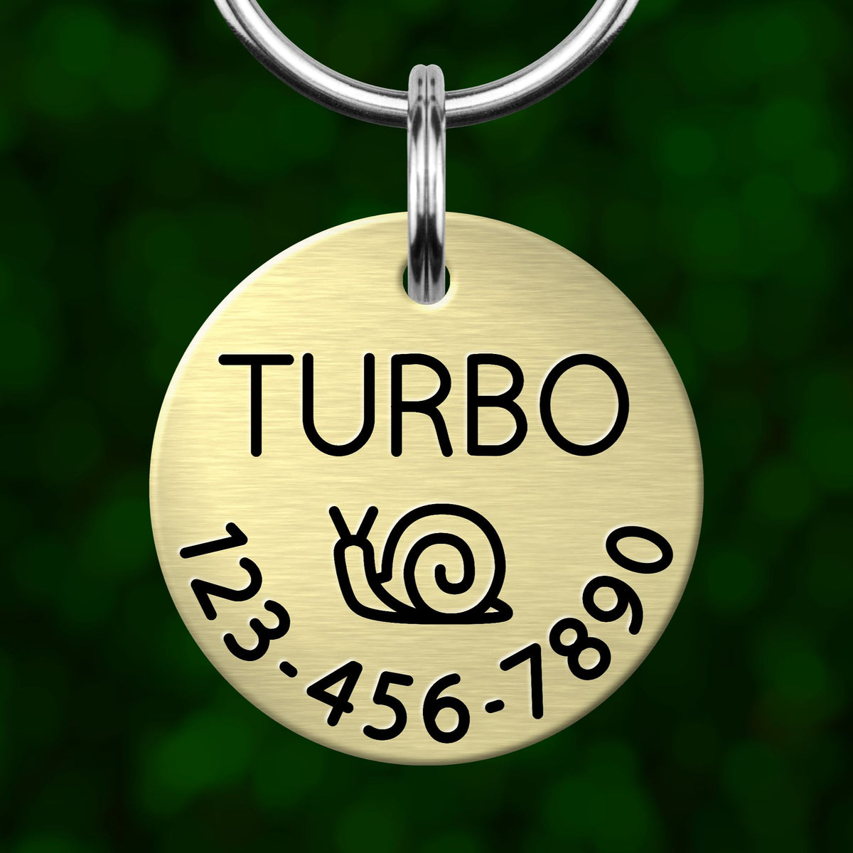 A round metal pet tag with the word "TURBO" printed on it, featuring a snail icon and a phone number below.