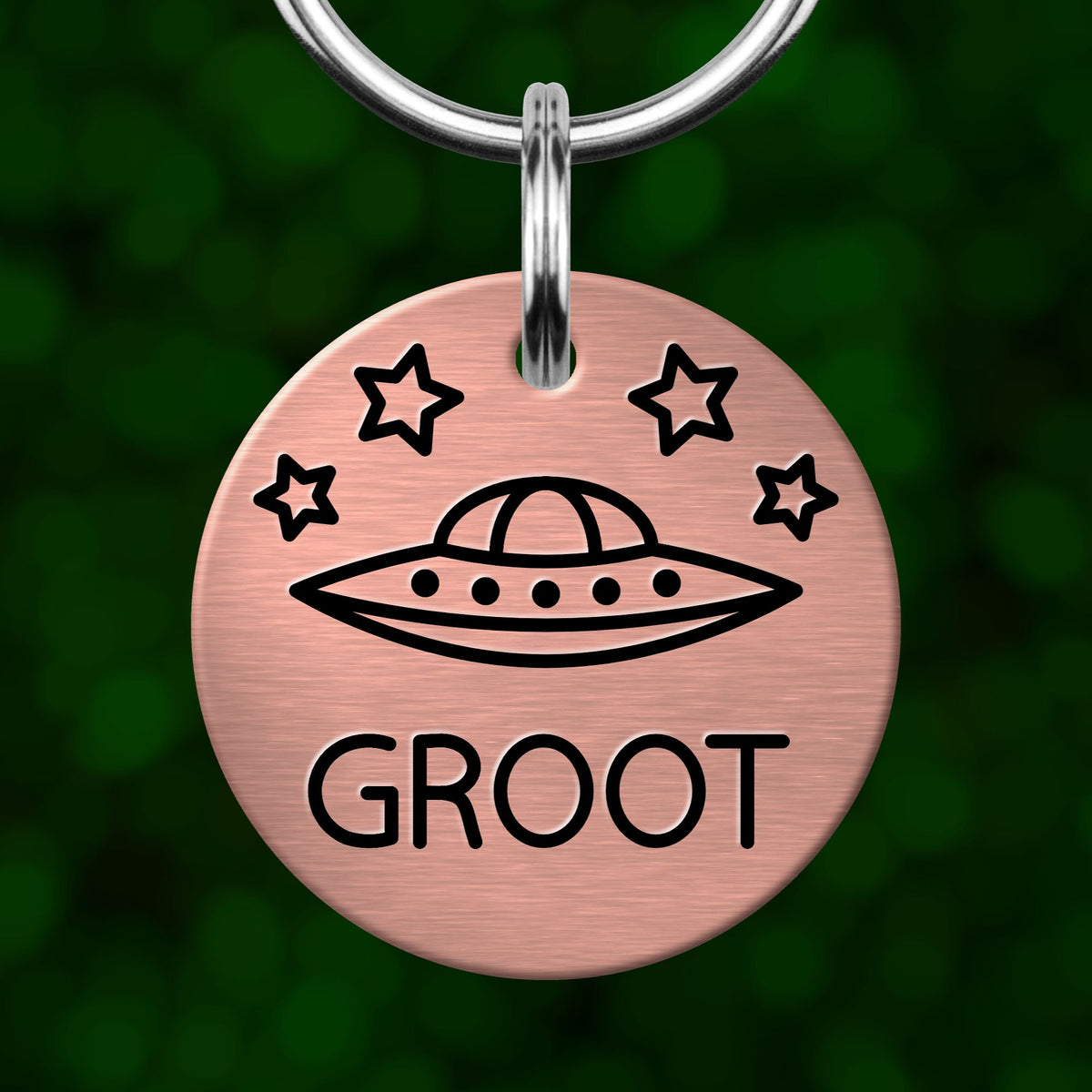 A round metal keychain tag with a graphic of an alien spacecraft and the word "GROOT" printed on it.