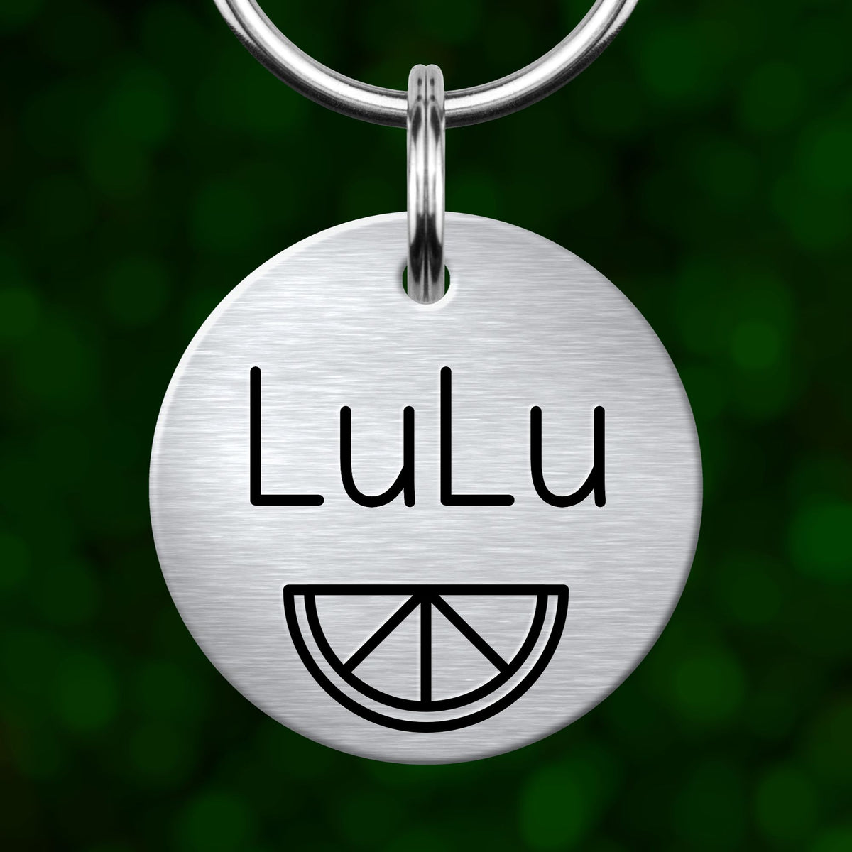 A silver-colored metal keychain tag with the name "Lulu" printed on it, along with a simple graphic of a lemon slice.