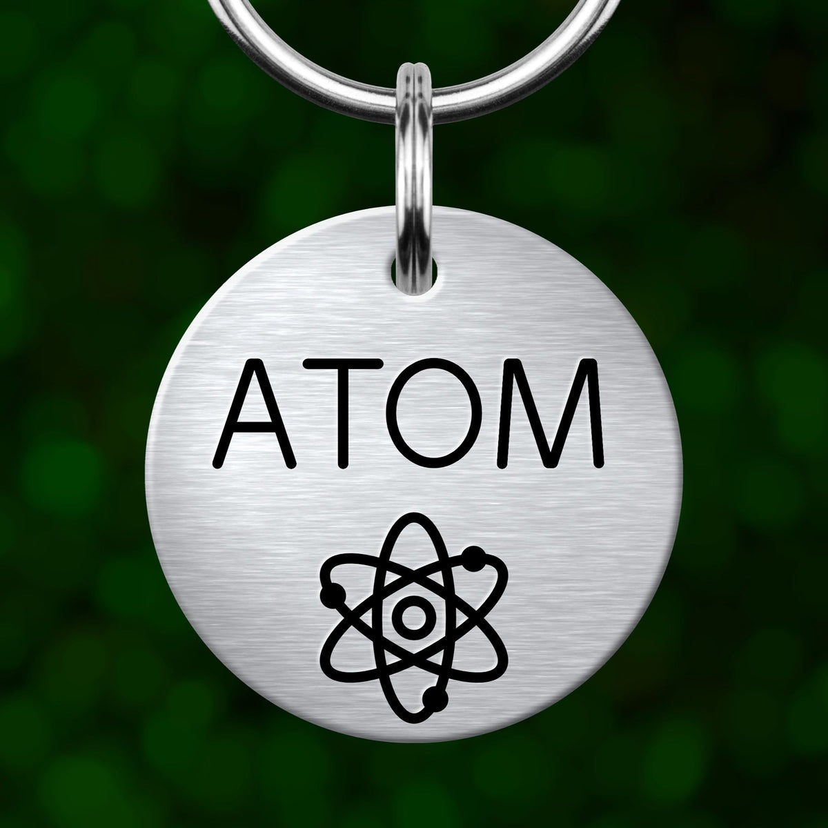 A silver circular tag with the word "ATOM" printed on it, along with an illustration of an atom.