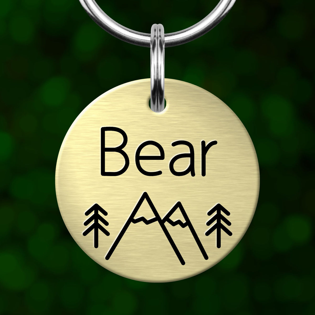A round metal keychain tag with the word "Bear" and mountain icons printed on it.