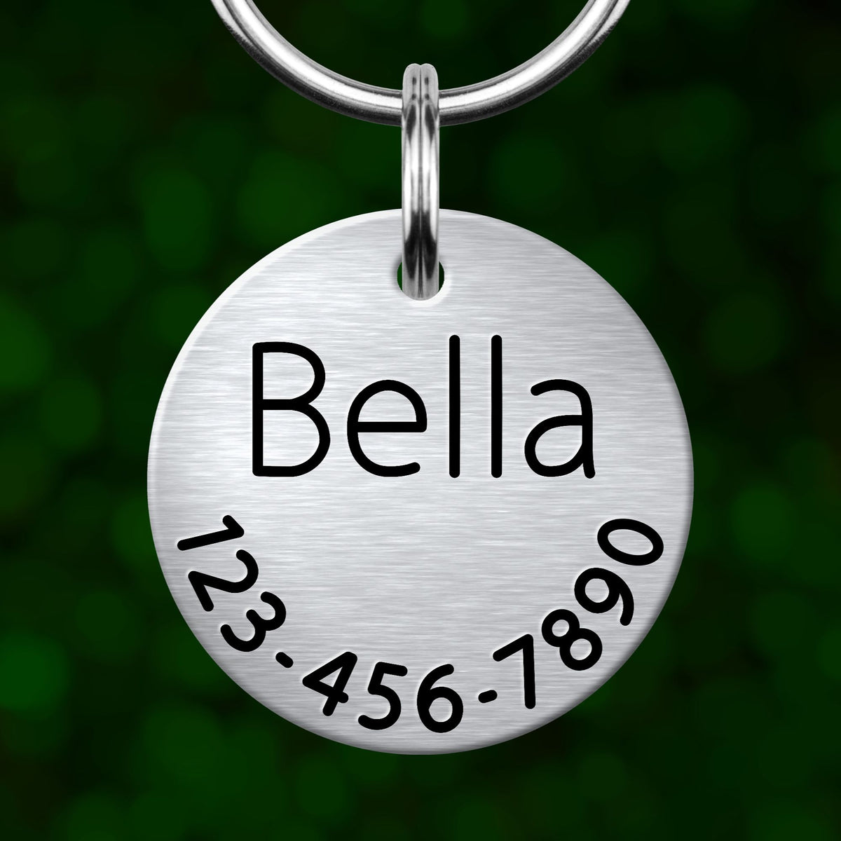 A silver metal name tag with the name "Bella" and a phone number "123-456-7890" printed on it.