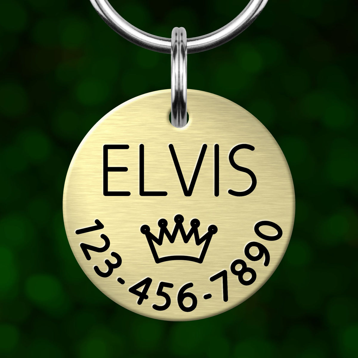 A round metal pet tag with the name "ELVIS" and a crown symbol printed on it.