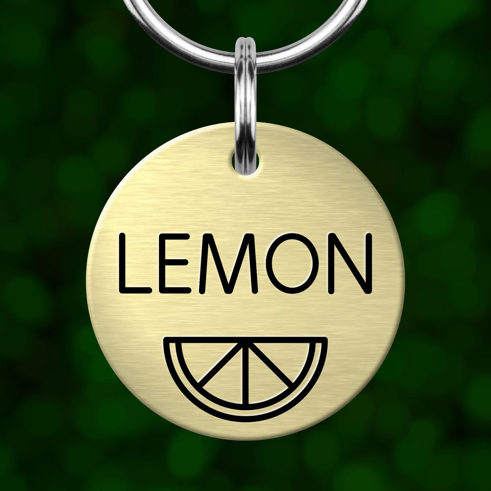 A round metal keychain tag with the word "LEMON" printed on it, along with a simple black and white lemon graphic.