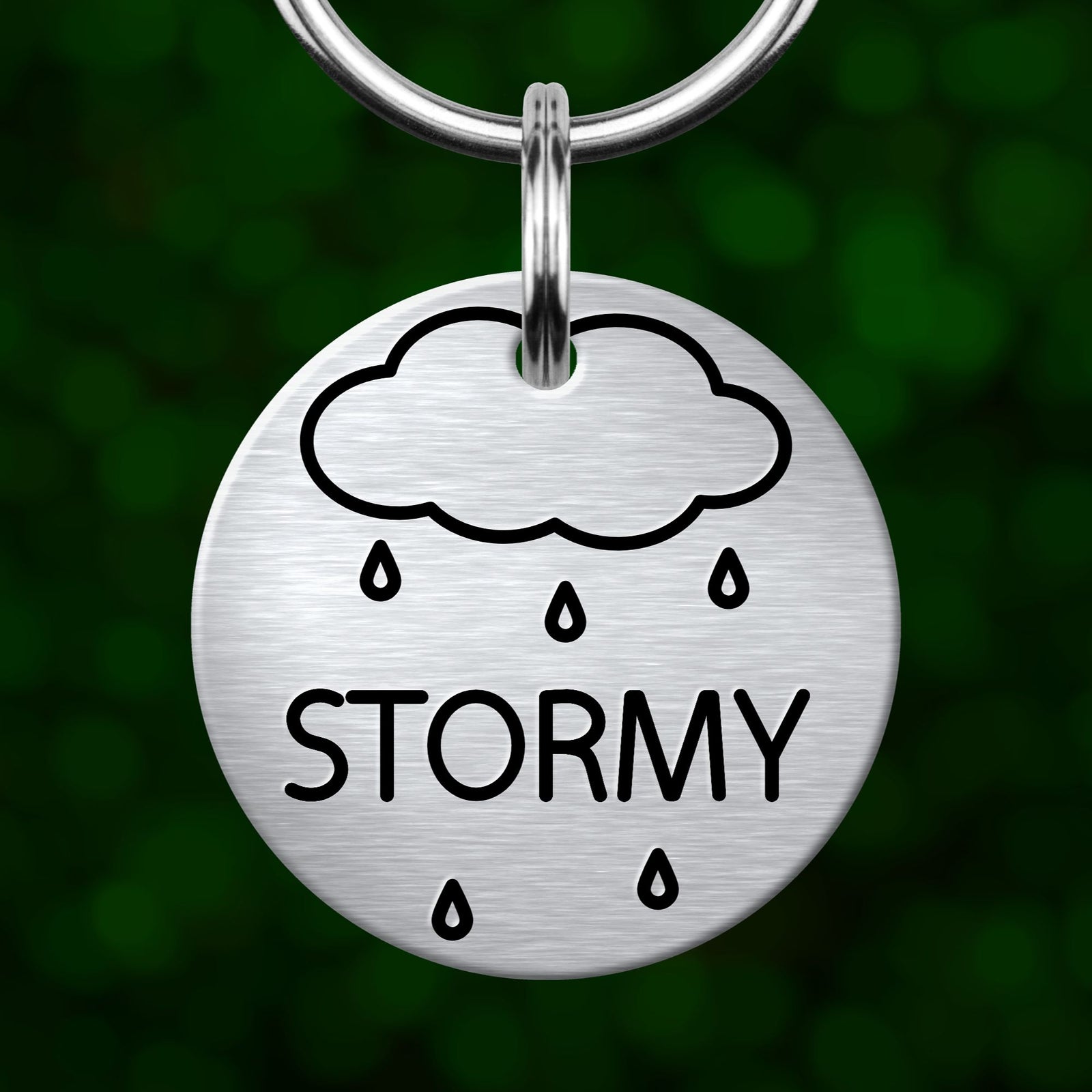 A round metal keychain tag with a cloud and rain symbol, and the word "STORMY" printed on it.