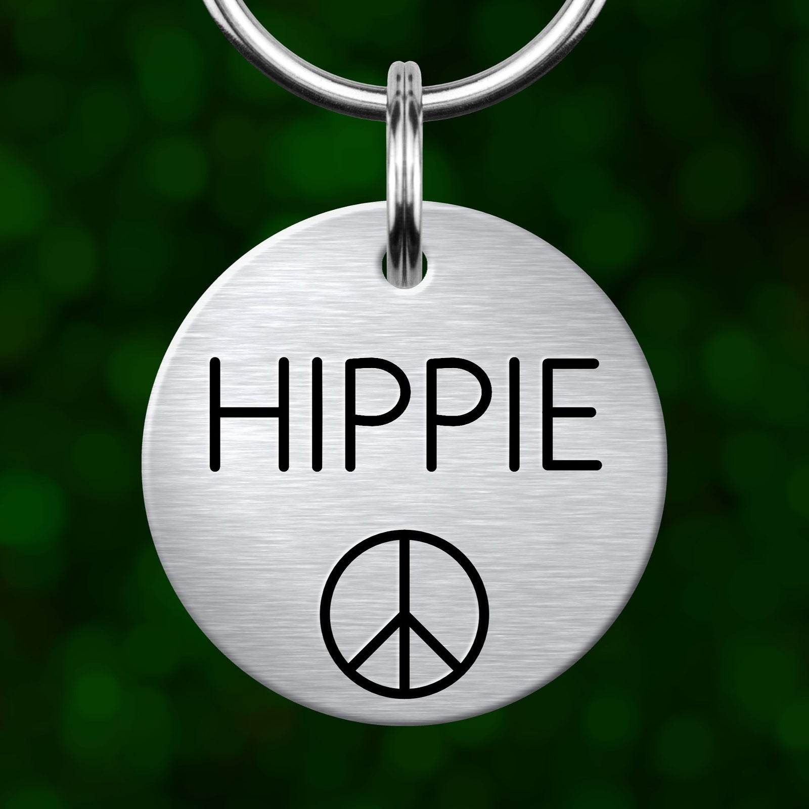 A silver metal dog tag with the word "HIPPIE" printed on it, along with a peace symbol.