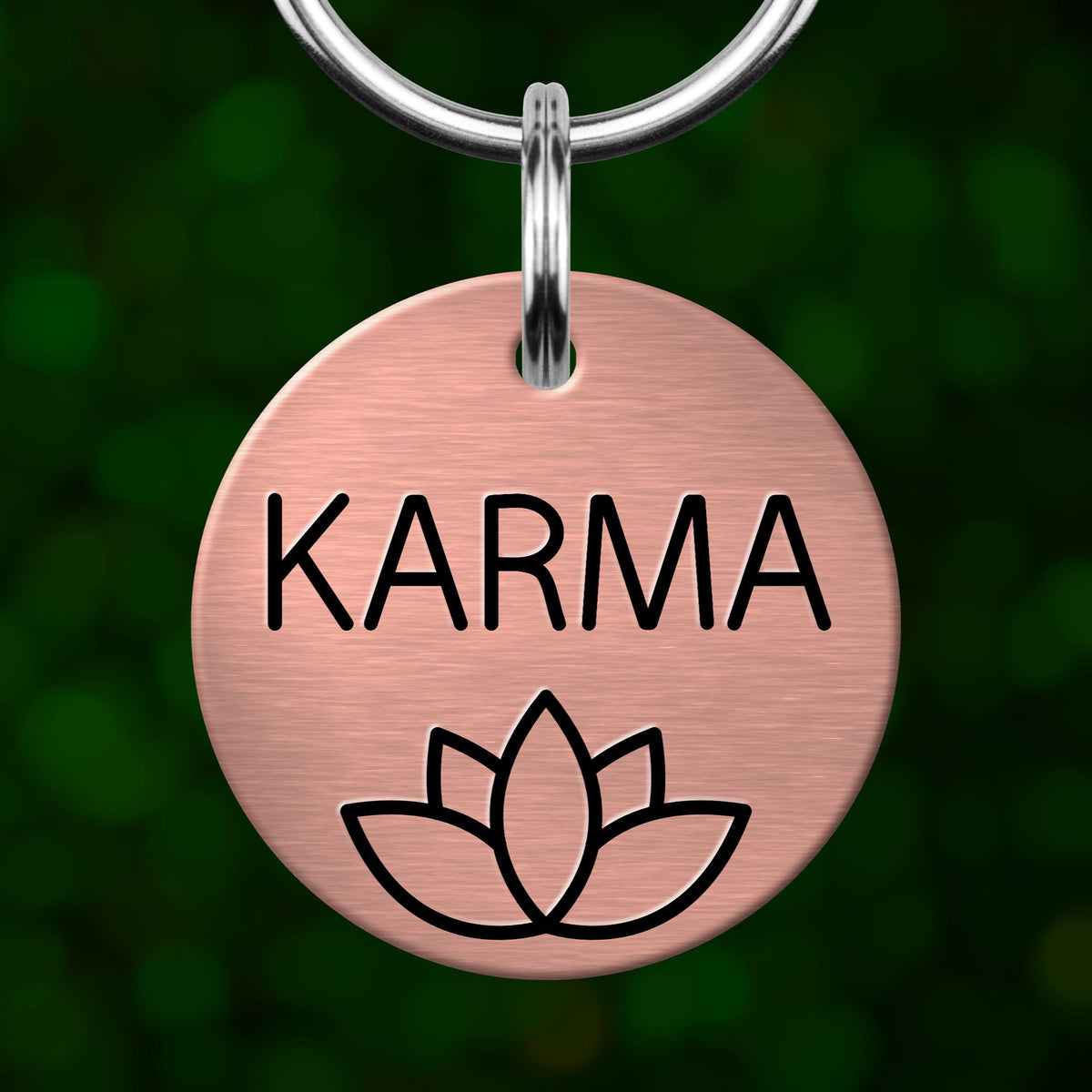 A pink metal keychain tag with the word "KARMA" and a lotus flower symbol printed on it.