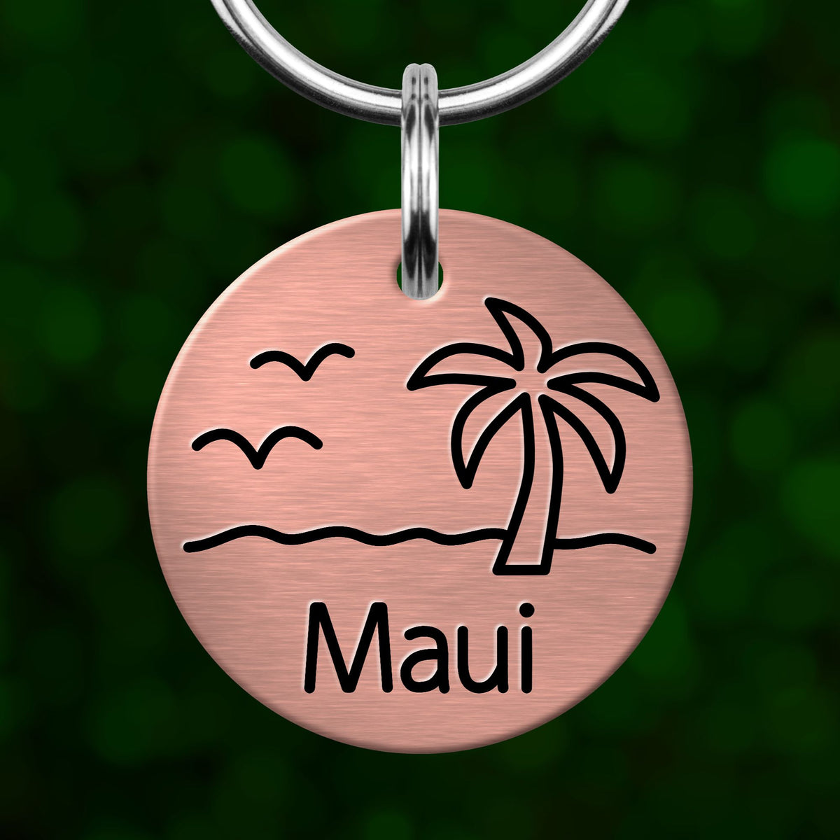 A round metal keychain with a palm tree and birds design, and the word "Maui" written on it.