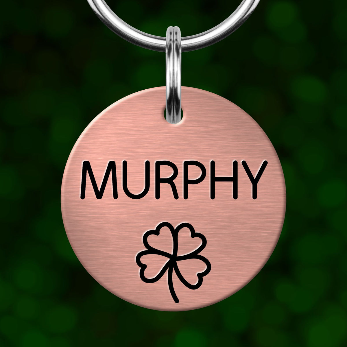A round metal pet tag with the name "MURPHY" printed on it, along with a cloverleaf symbol.