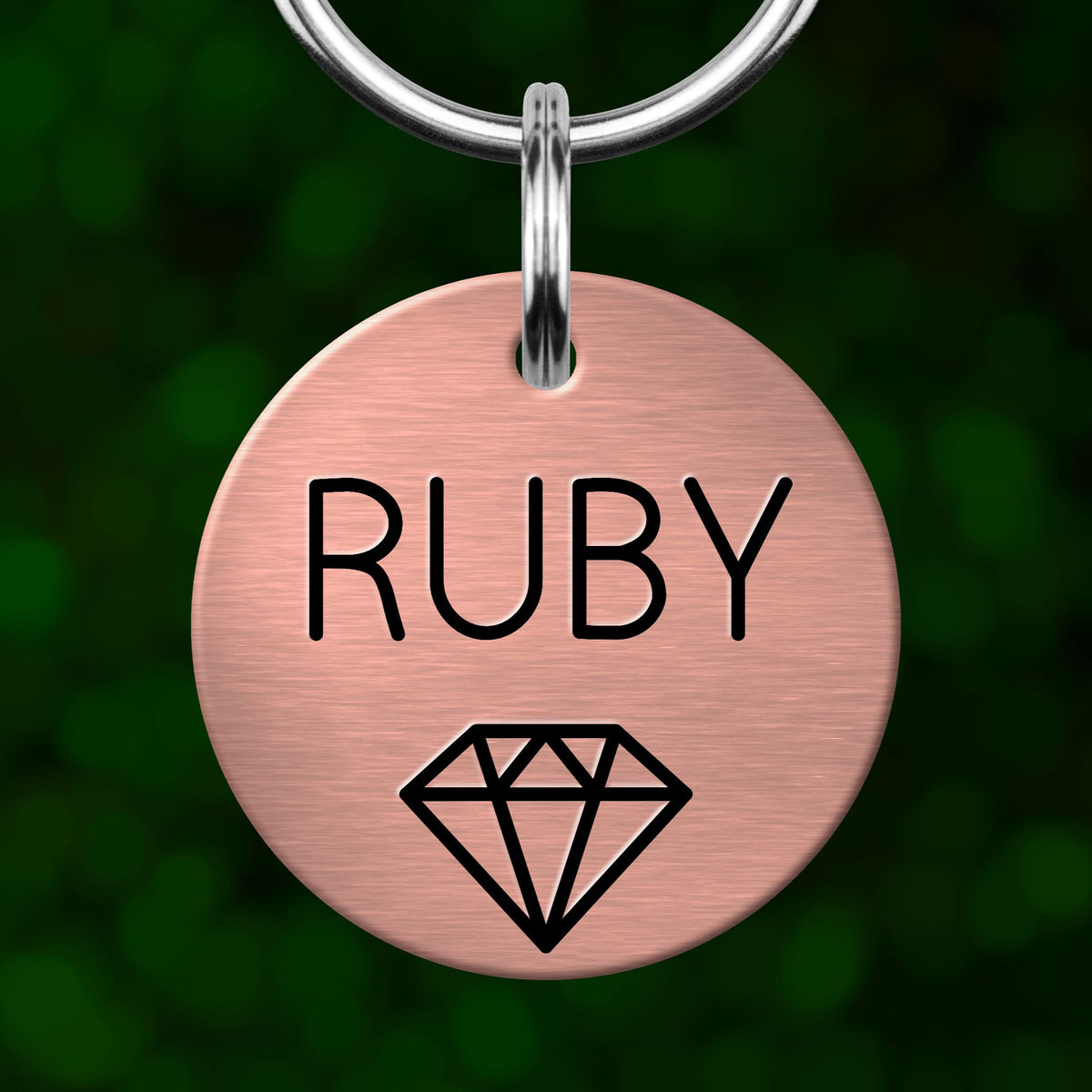 A round metal pet tag with the name "Ruby" printed on it, along with a small diamond symbol.