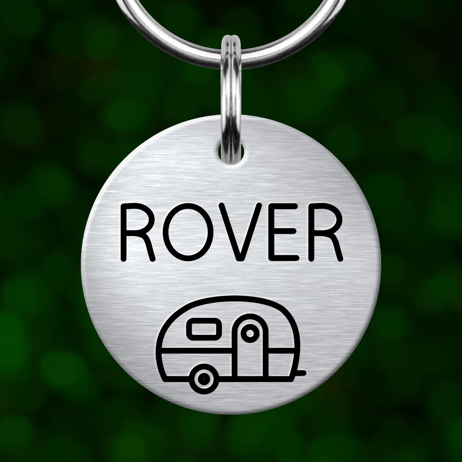 A round metal pet tag with the name "Rover" printed on it, along with a simple line drawing of a camper van.