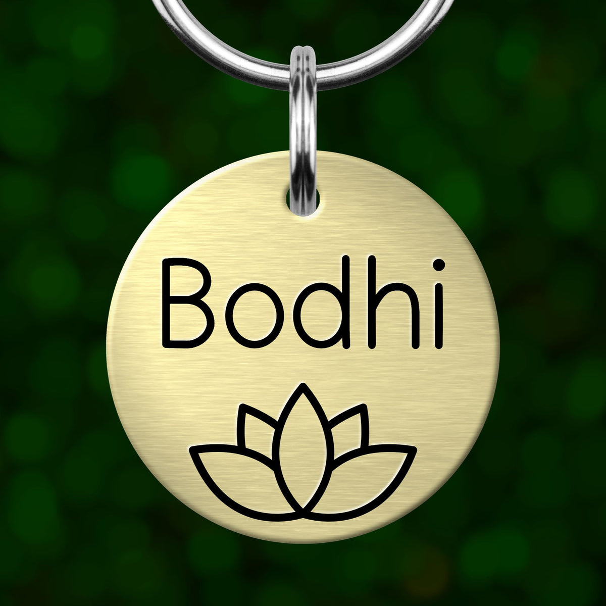 A round metal pet tag with the name "Bodhi" and a lotus flower symbol printed on it.