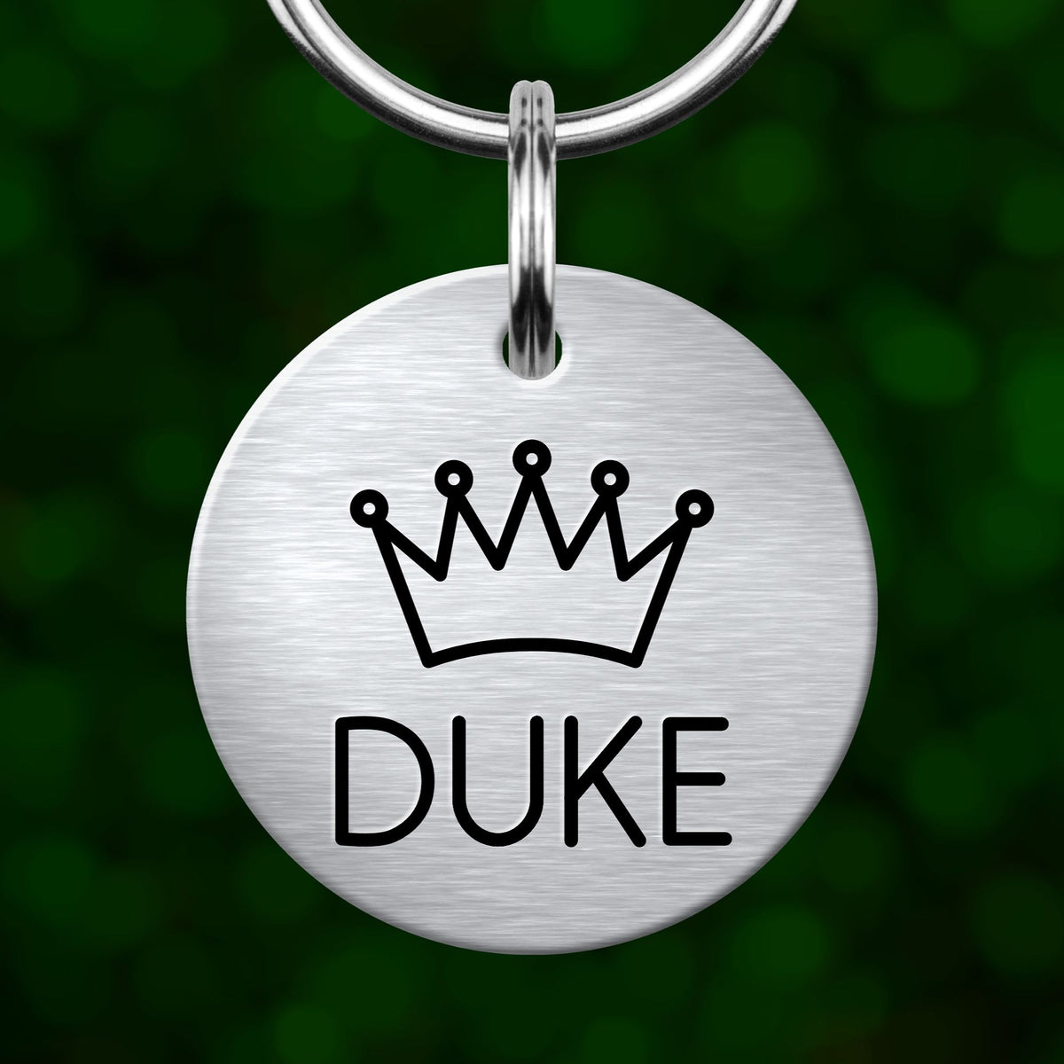 A silver metal keychain tag with a crown symbol and the word "DUKE" printed on it.