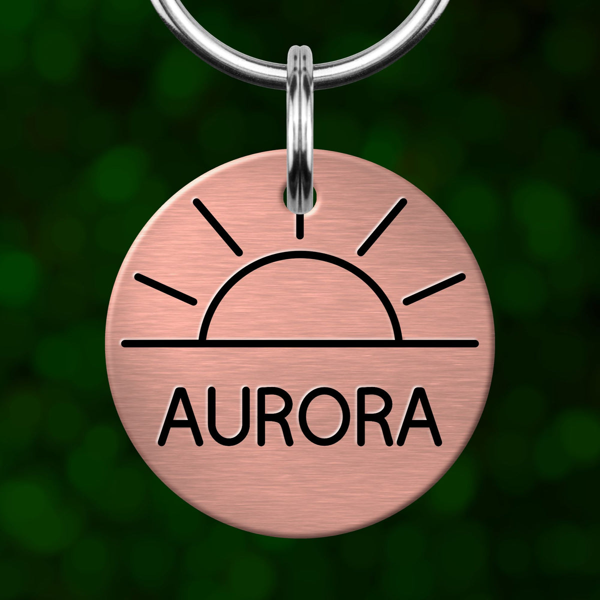 A copper-colored keychain tag with a sun-like symbol and the word "AURORA" printed on it.
