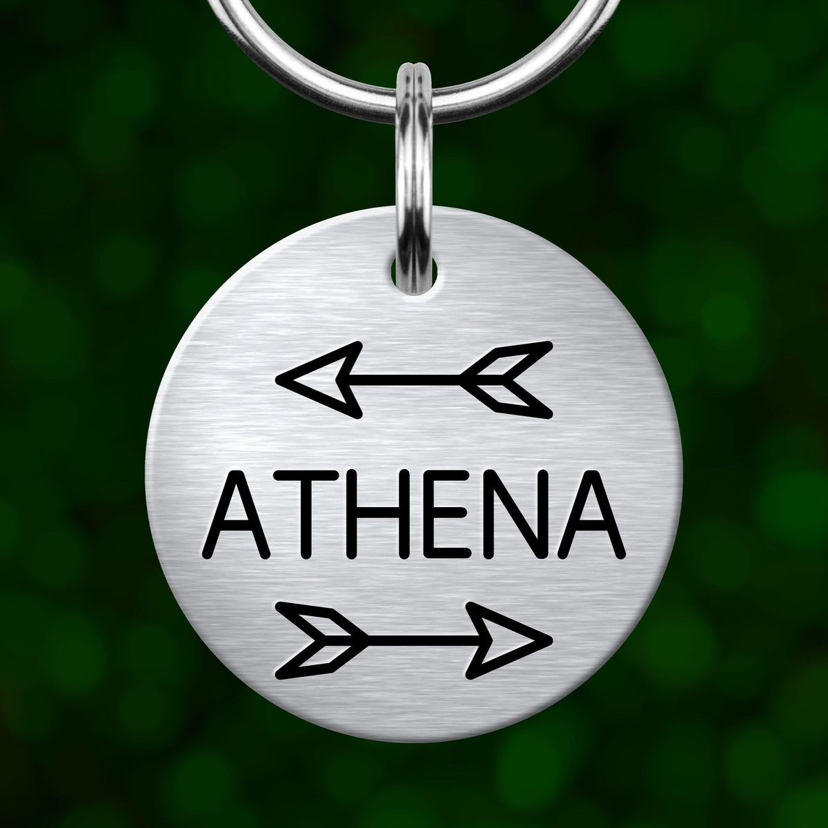 A silver circular keychain tag with the word "ATHENA" written on it, along with two arrows pointing in opposite directions.