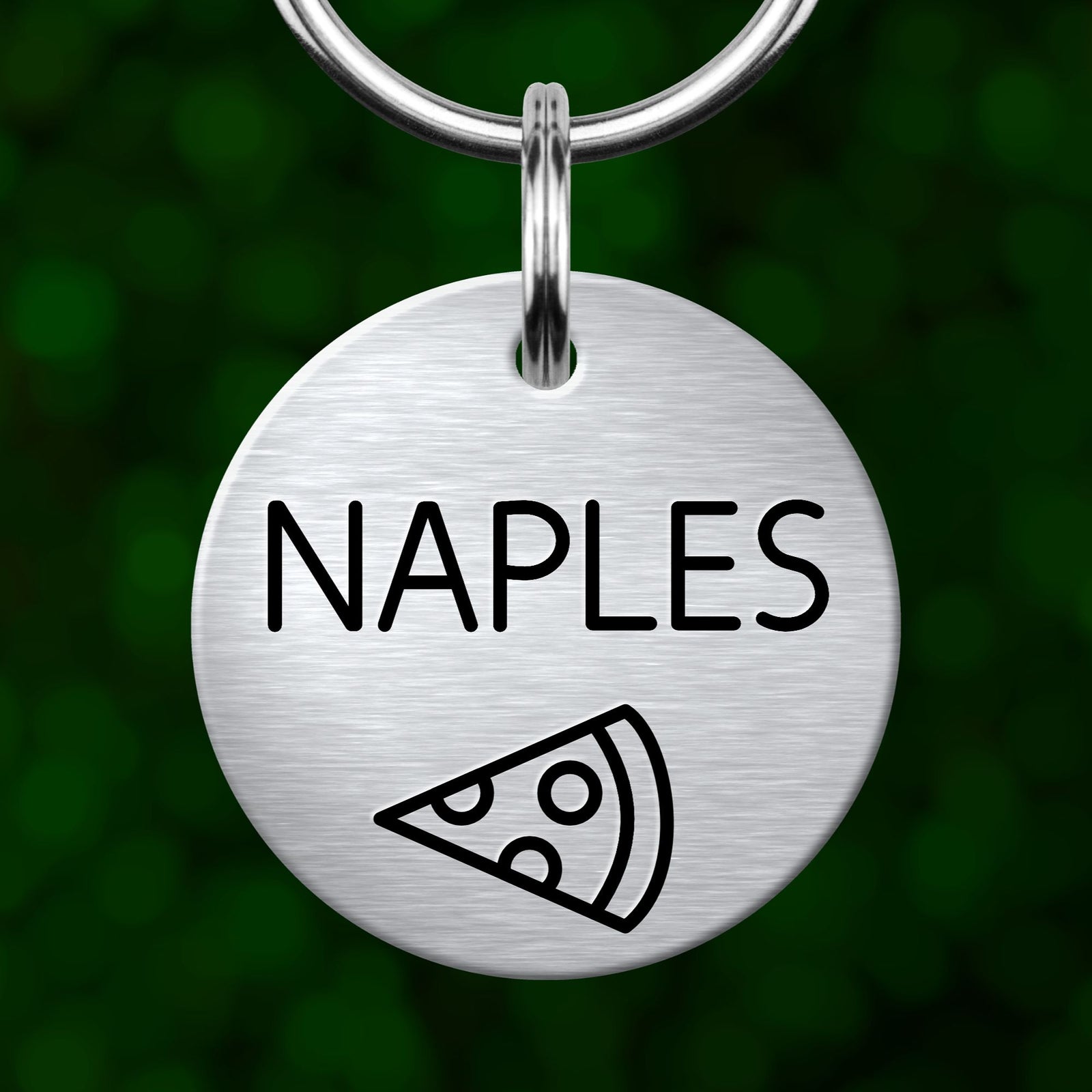 A silver-colored metal keychain with the word "NAPLES" printed on it, along with a simple black pizza slice icon.