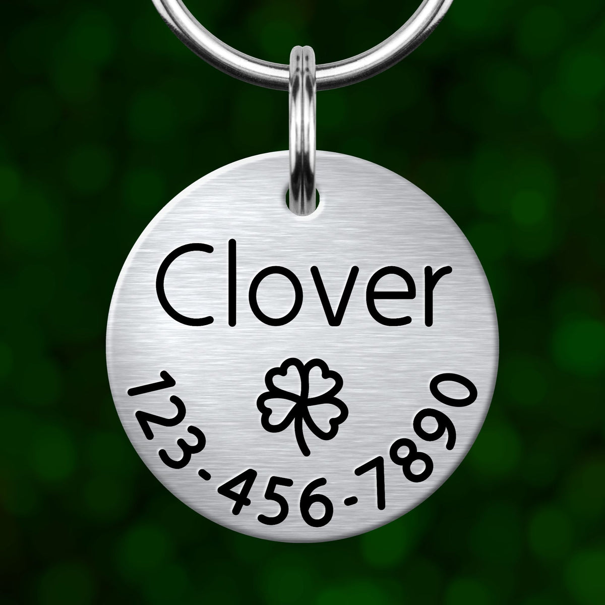 A silver-colored keychain tag with the name "Clover" and contact information, including a phone number and a clover symbol.