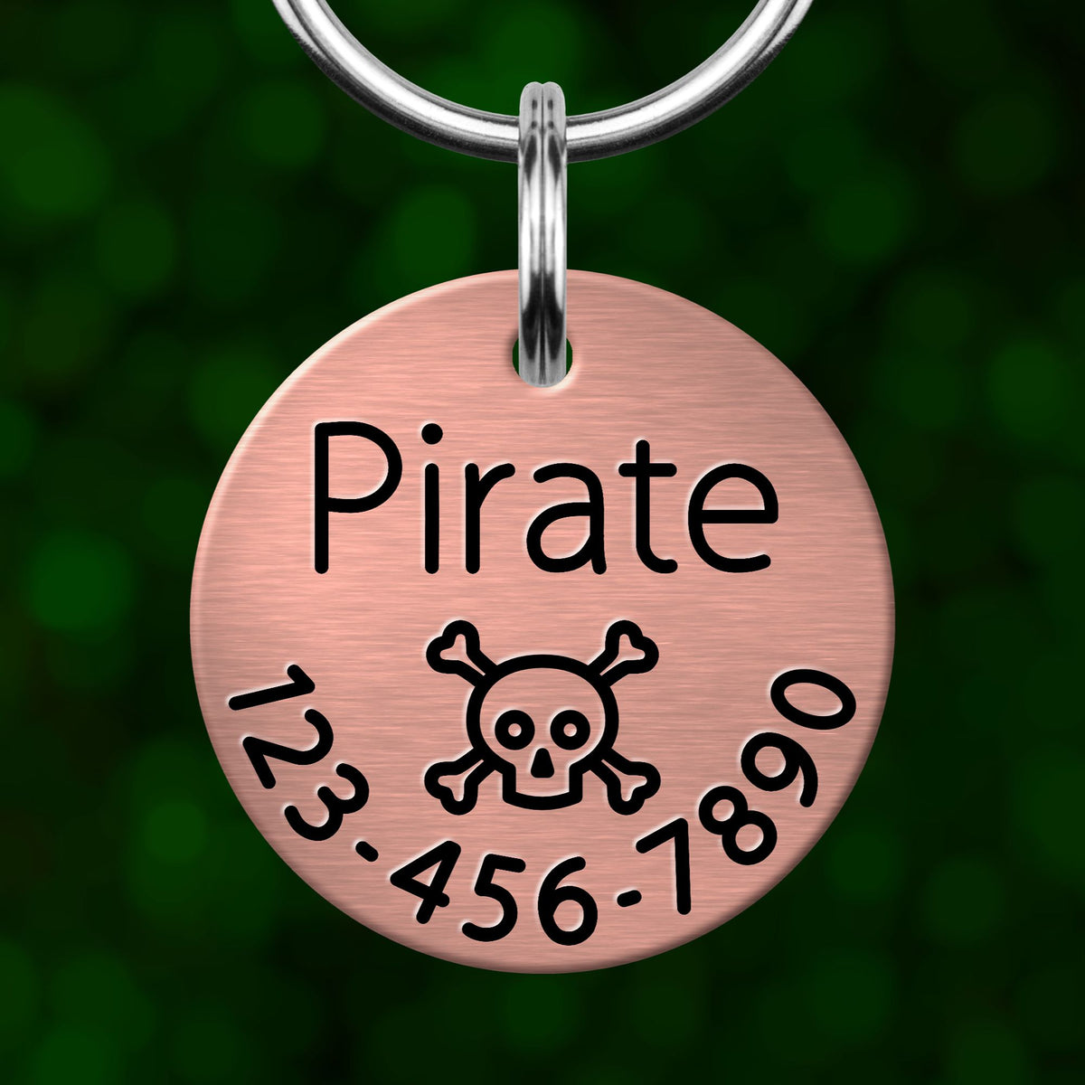 A round metal pet tag with the name "Pirate" and a skull and crossbones symbol, along with a phone number.