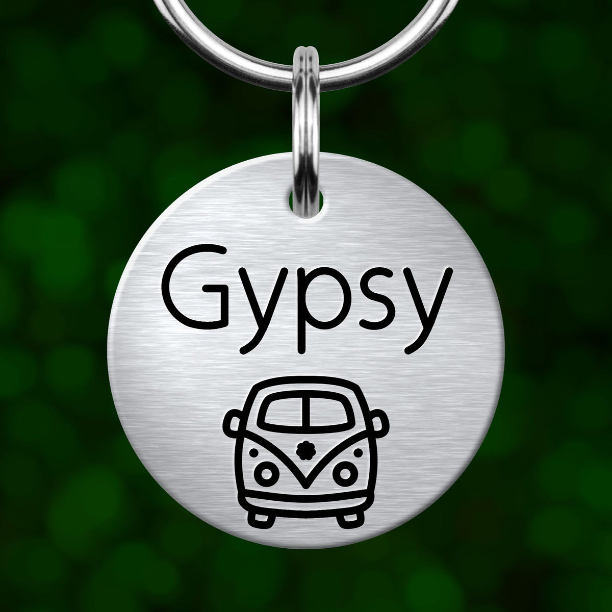 A round metal pet tag with the word "Gypsy" printed on it, along with a simple black and white illustration of a van below the text.