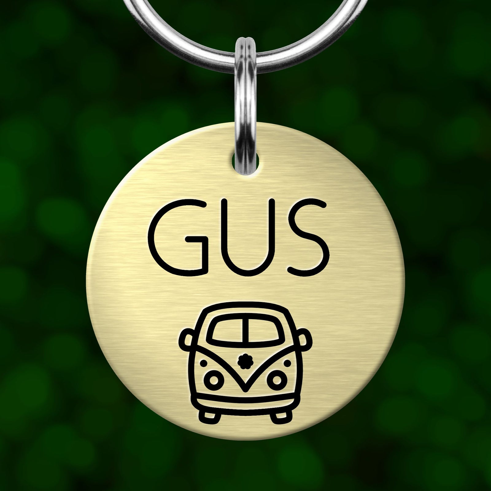 A round metal keychain tag with the name 'GUS' and a small illustration of a van.