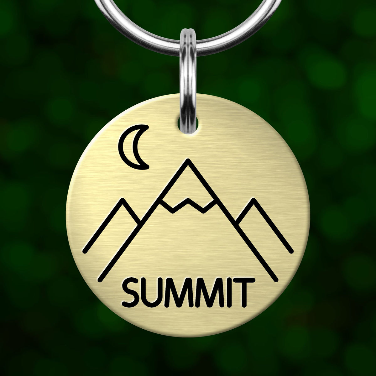 A round metal keychain tag with a mountain and crescent moon symbol, and the word "SUMMIT" printed on it.